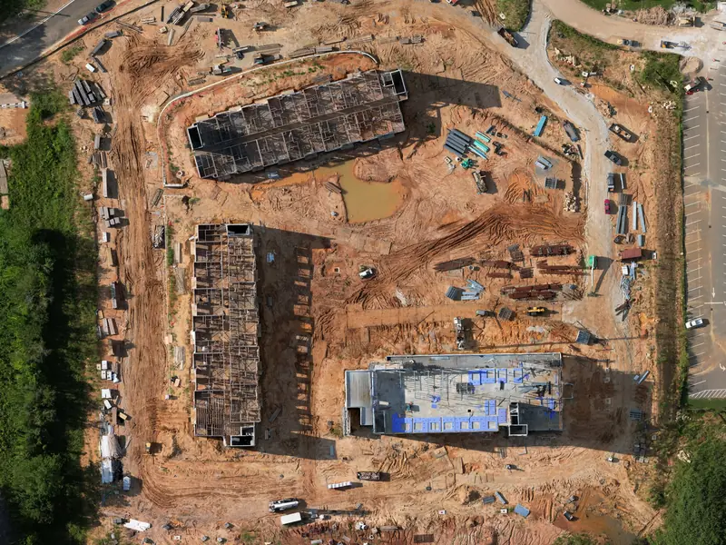 Overhead drone map of a hotel and two wings under construction, with materials staged around the site.